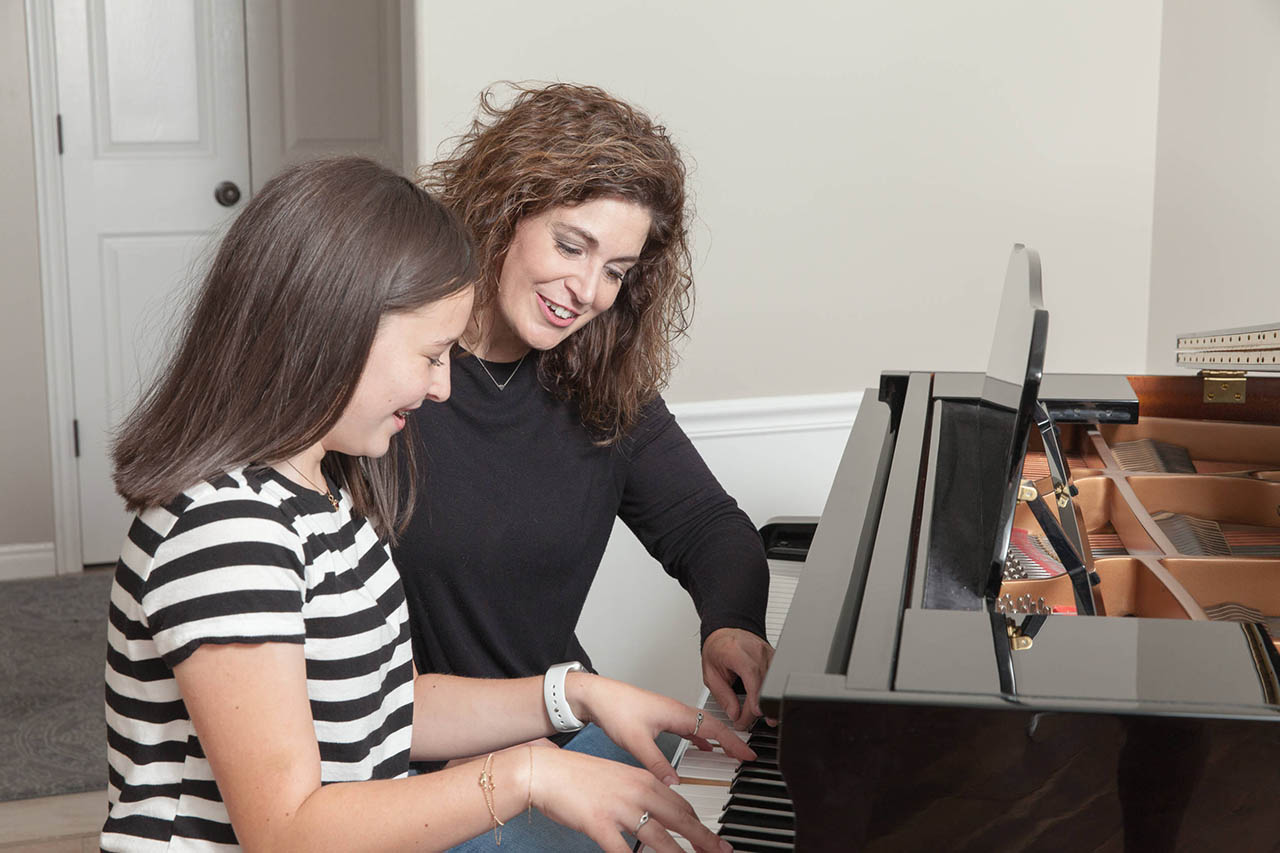 Woman teaching piano to a young adult