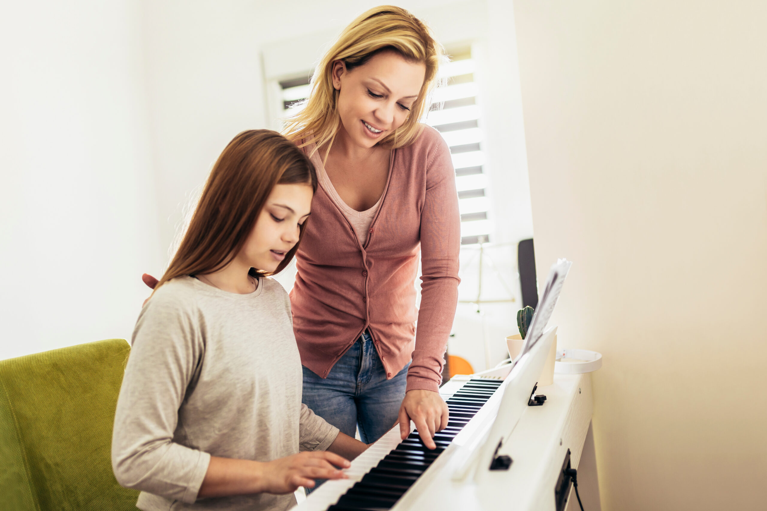 Girl learning play piano with teacher