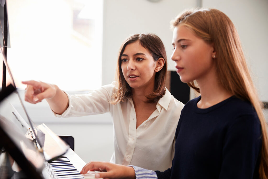 Piano Teacher Helping a Student At the Piano