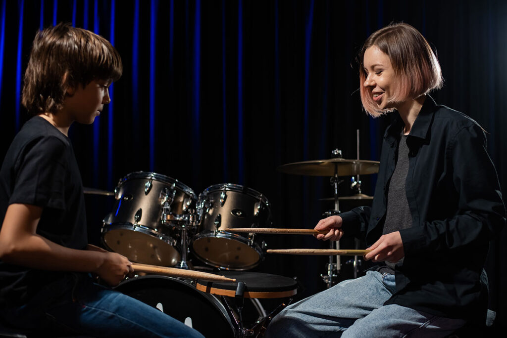 Female drum teacher with young male student practicing