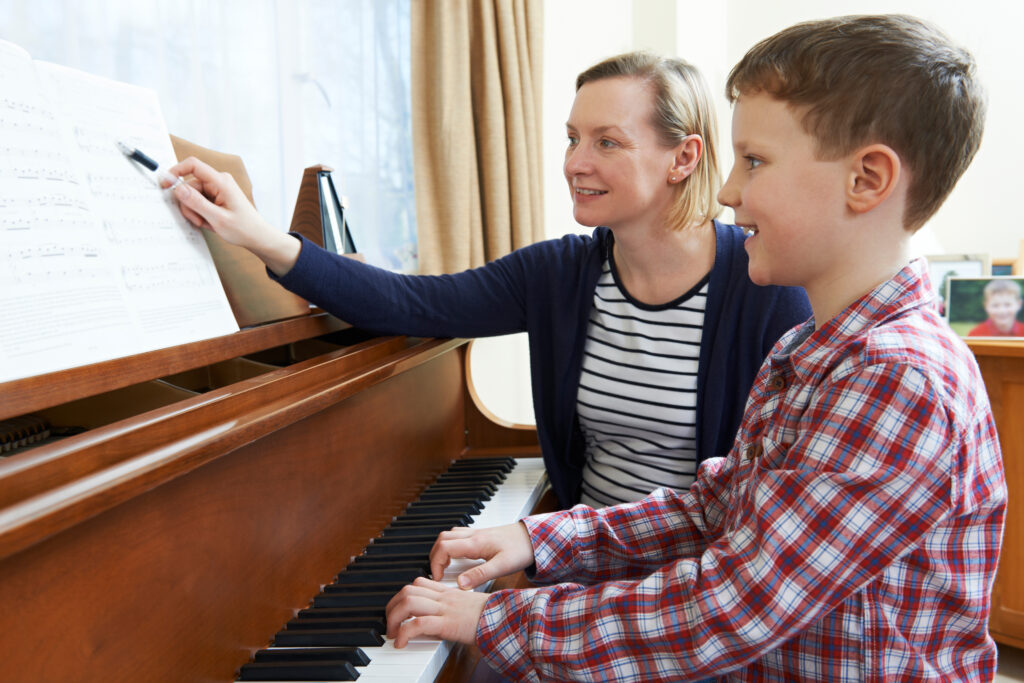 Boy with music teacher having piano lesson for kids