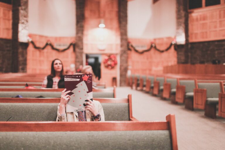 girl in recital hall with a piano music book in front of her face to hide