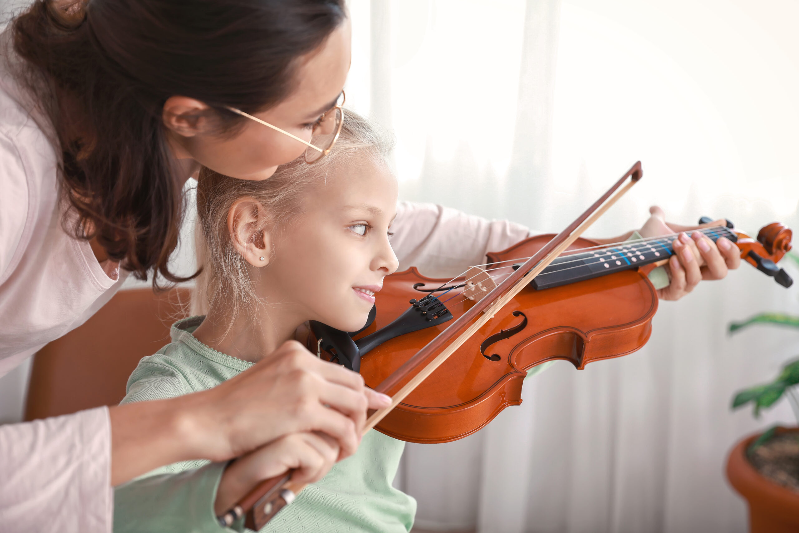 music teacher giving violin lessons to little girl