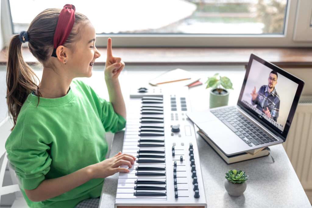 A girl learns to play the piano with a teacher online, remote learning music