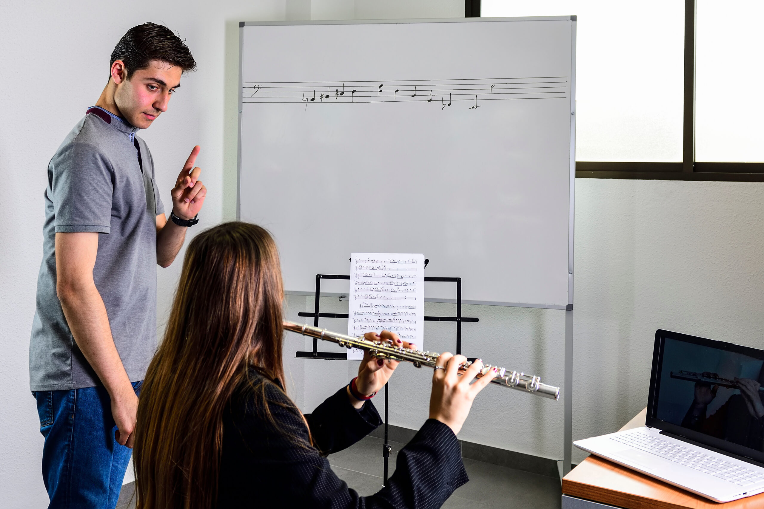 Teacher teaching adult woman how to play the flute