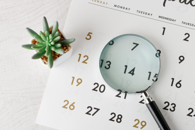 Calendar with a magnifying glass and small plant. How long does it take to learn to play the piano?